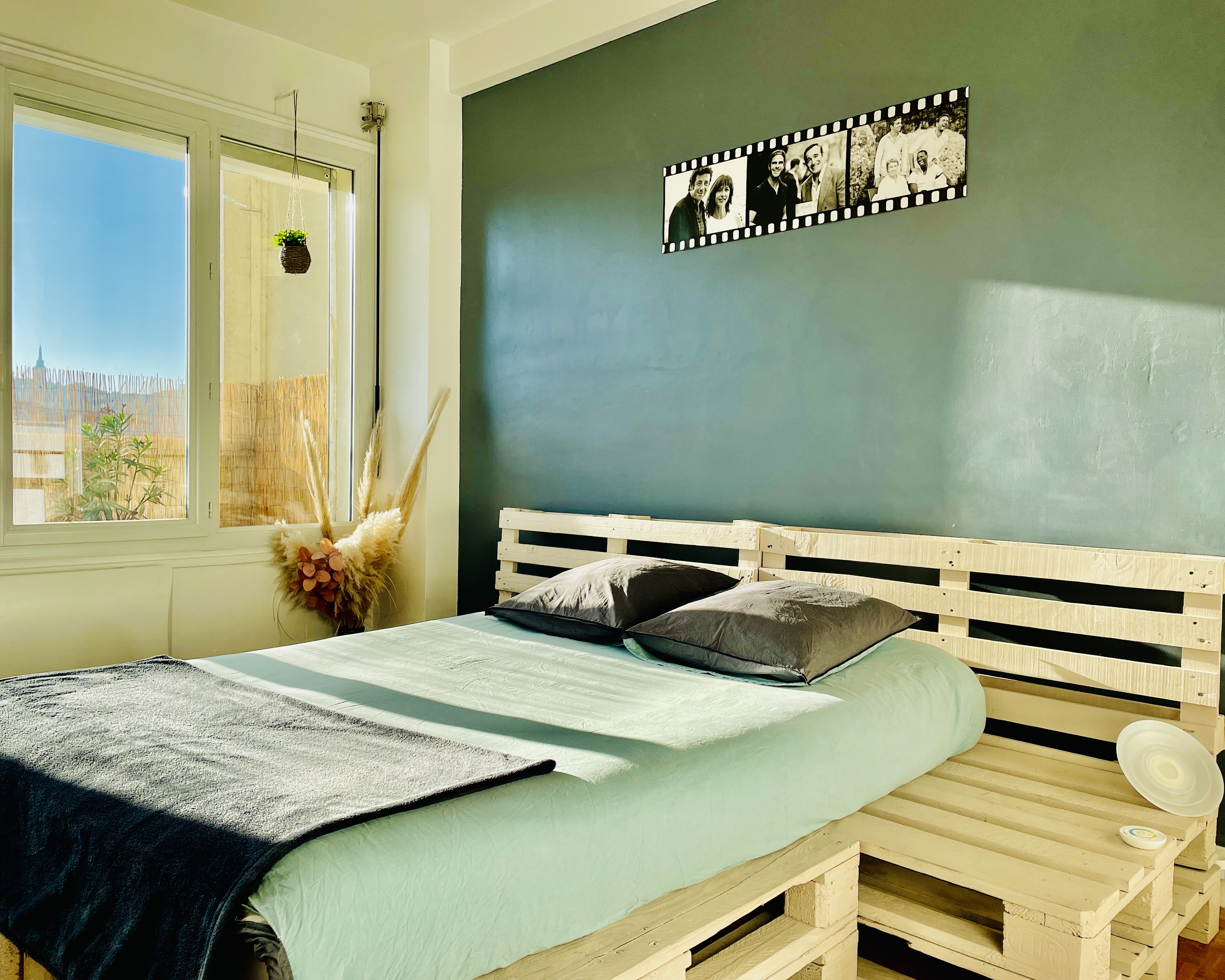 alt="Chambre lumineuse avec vue sur la ville, lit confortable et décoration naturelle à l’App’Art"