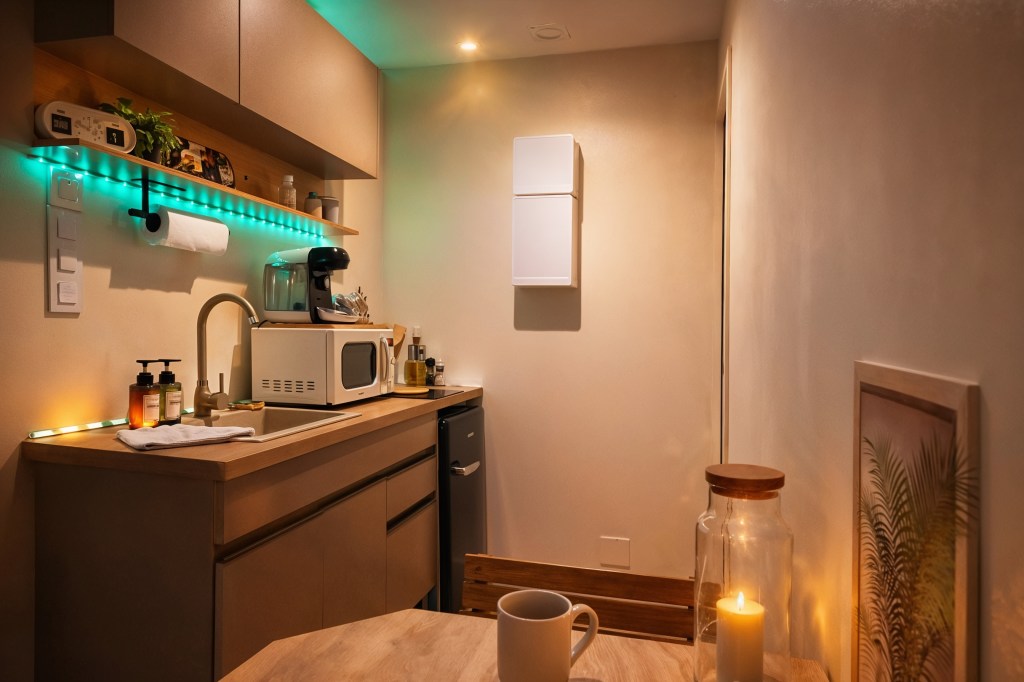 Kitchenette moderne équipée avec micro-ondes, machine à café, mini frigo et éclairage d’ambiance dans studio à Angoulême